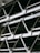 A close-up view of an industrial structure displaying several parallel metallic beams and cross-braces arranged in a geometric pattern. The beams are primarily composed of metal and exhibit a clean, angular design. A light fixture is visible at the top left corner.