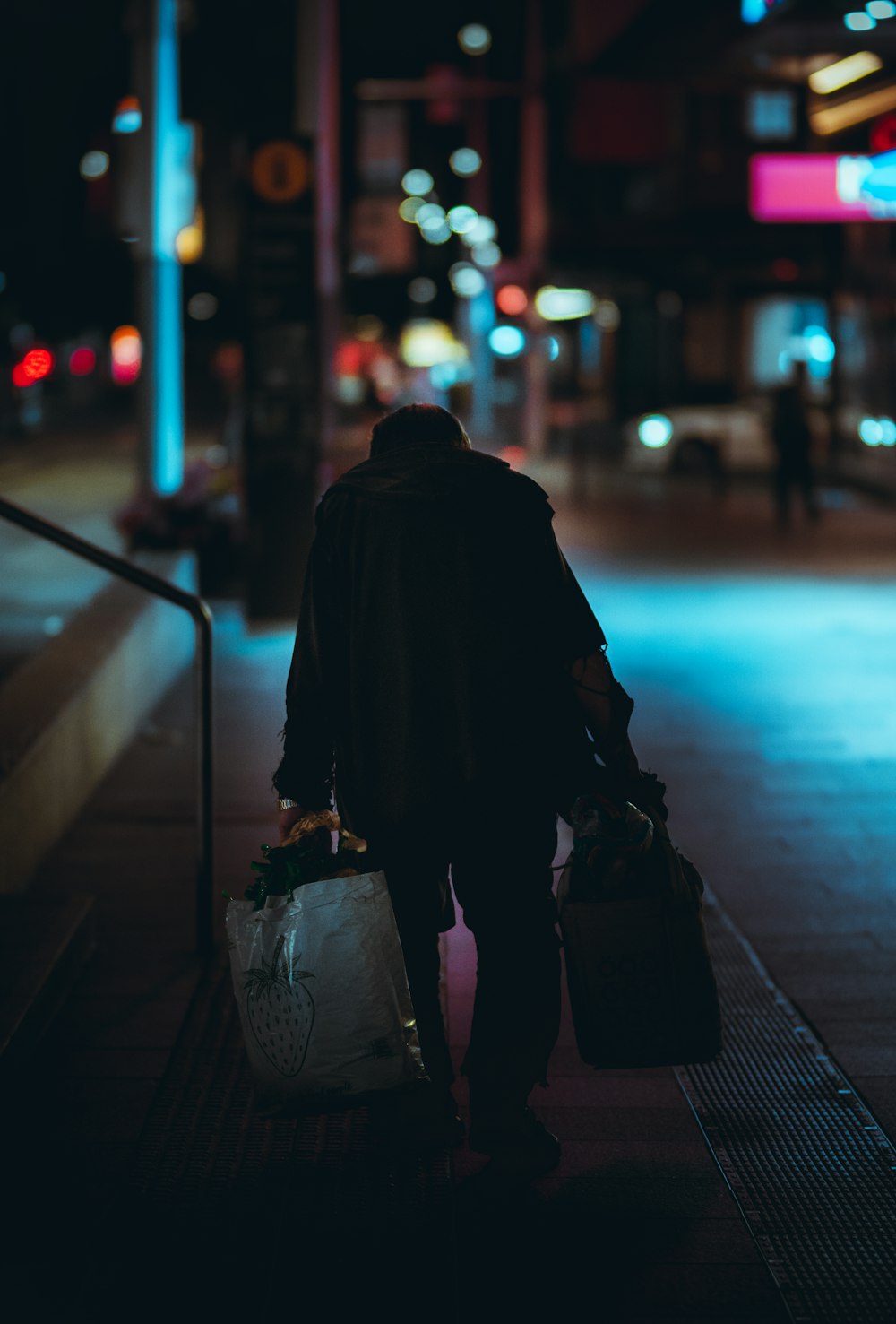 person in black coat standing on sidewalk during night time