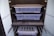 A dark-colored storage cabinet with two transparent plastic containers on separate shelves. Below them, there is a drawer with foam inserts, possibly for organization. The bottom section has metal rods, likely for hanging items, and another plastic container.