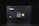 A black electronic safe with a keypad and a small digital display. The safe has a prominent brand logo on the front and a warning label at the top left corner. It is placed in a dark environment, enhancing its prominence and security features.