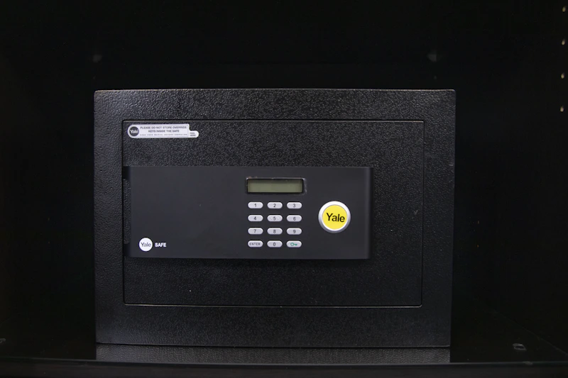 A black electronic safe with a keypad and a small digital display in a dark environment.