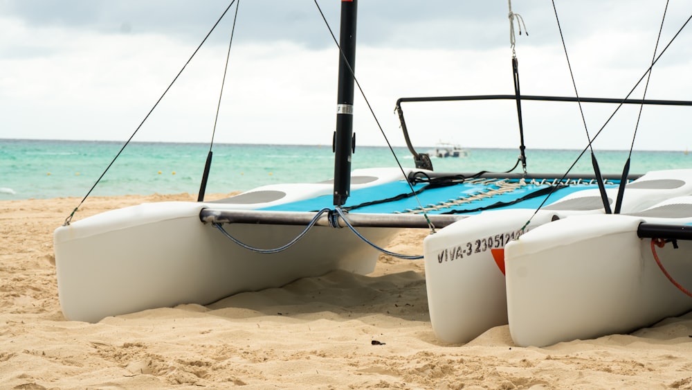 white and black sailboat on white sand during daytime