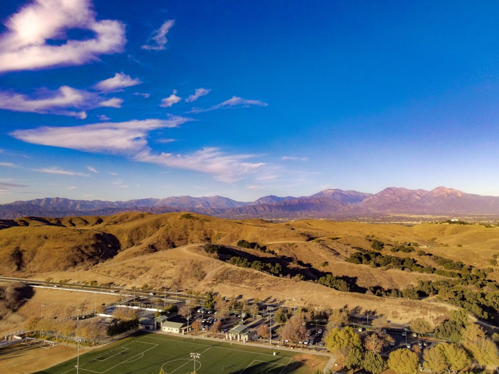 green grass field near mountain under blue sky during daytime