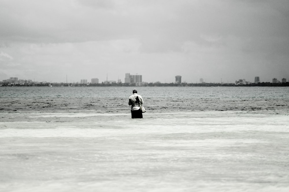 person in black and white jacket standing on sea shore