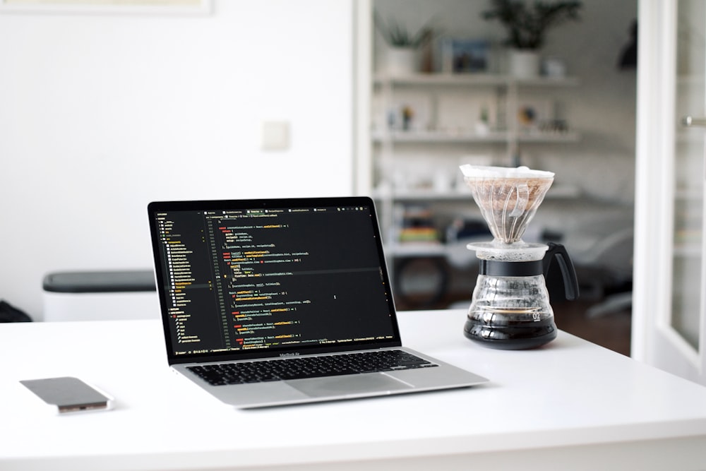 black laptop computer beside clear glass cup