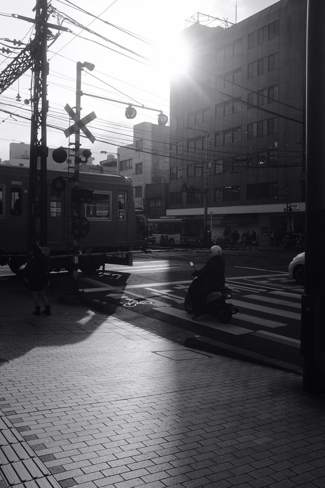 grayscale photo of woman sitting on bench near train