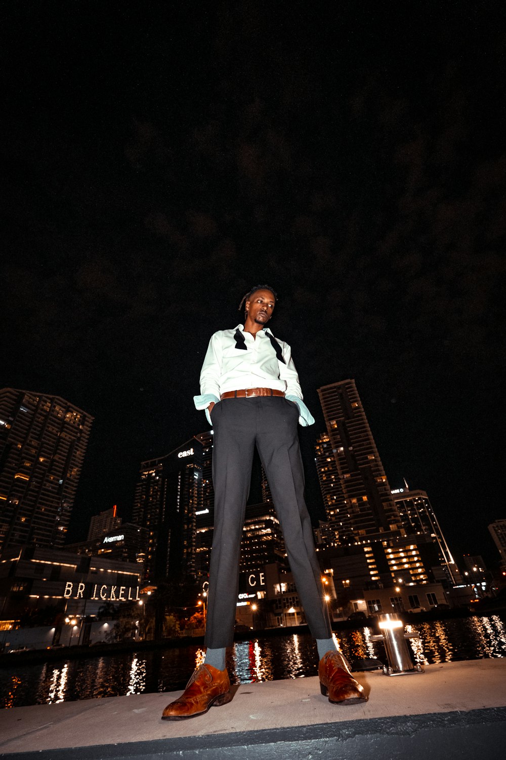 man in white dress shirt and black pants standing on top of building during night time