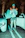 woman in teal zip up jacket and white pants standing beside white car