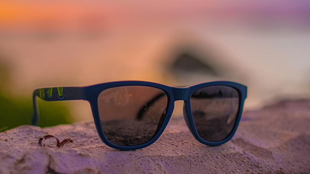 blue framed sunglasses on brown sand