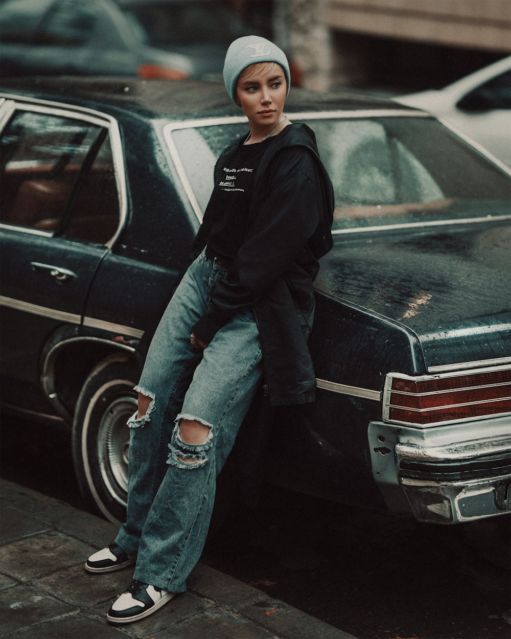 man in black jacket and blue denim jeans standing beside black car