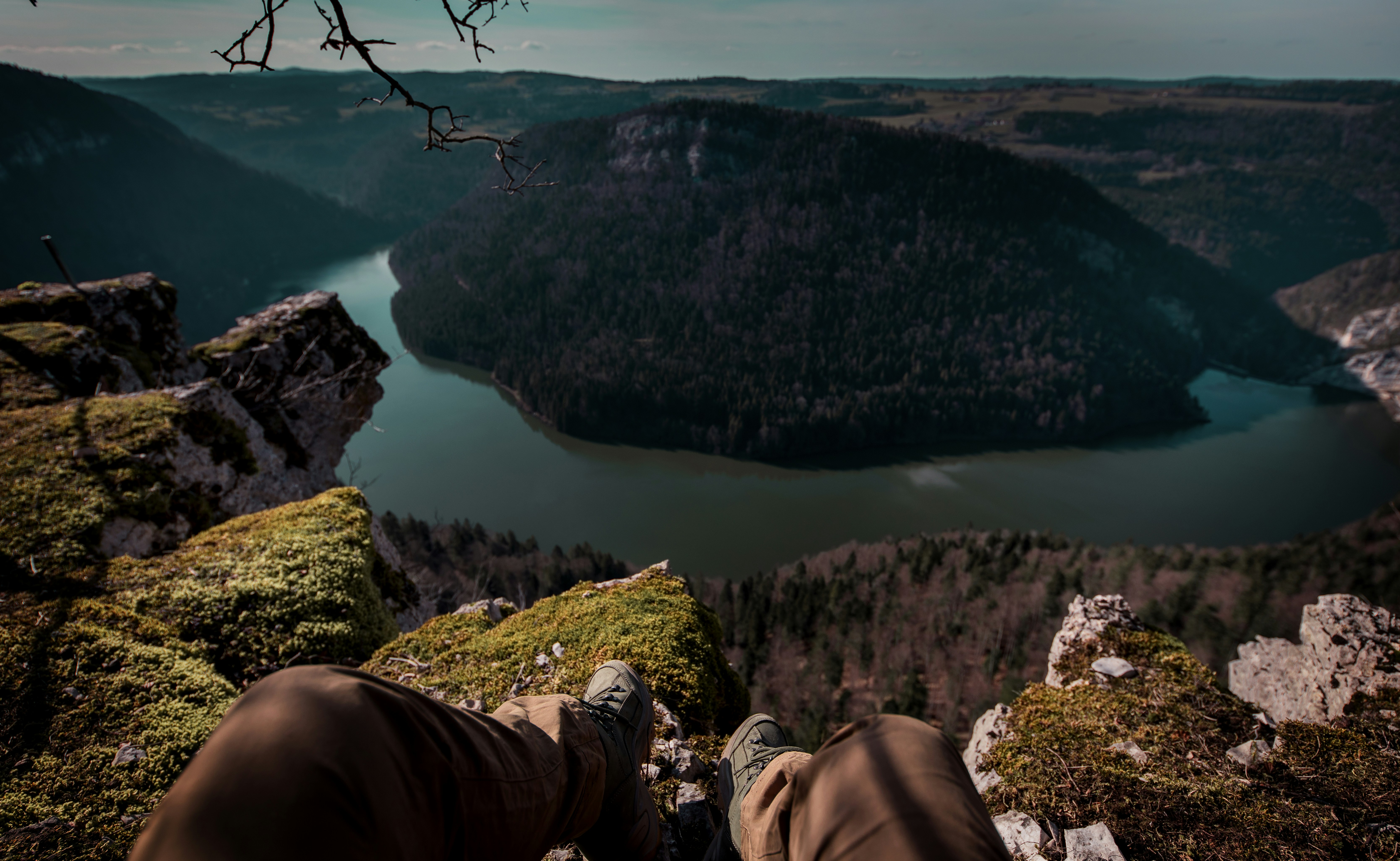 person in brown pants sitting on green grass field near lake during daytime