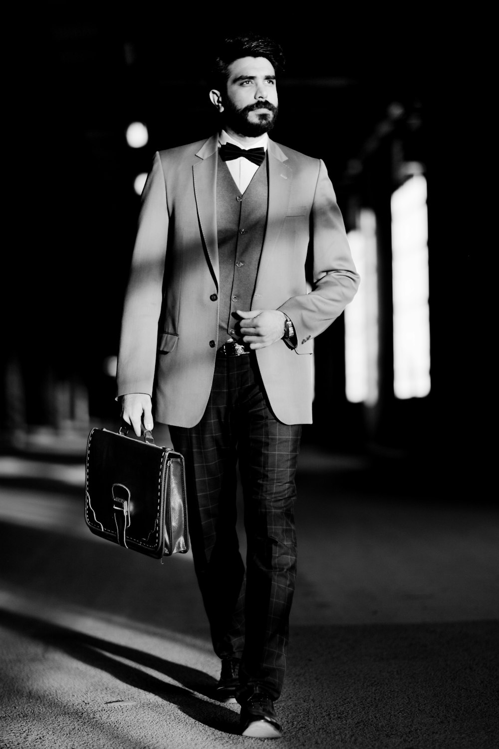 man in black suit jacket and black pants holding black leather handbag