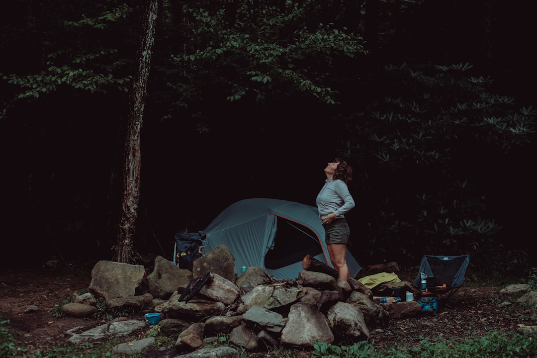 man in gray t-shirt and gray pants standing near gray tent during daytime