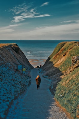 2 person walking on pathway between green grass field during daytime