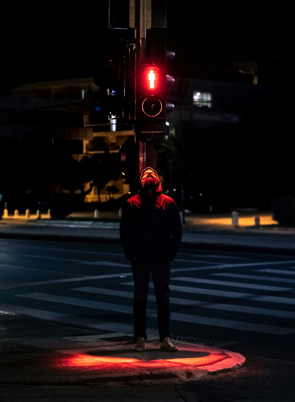 man in black jacket standing on pedestrian lane during night time