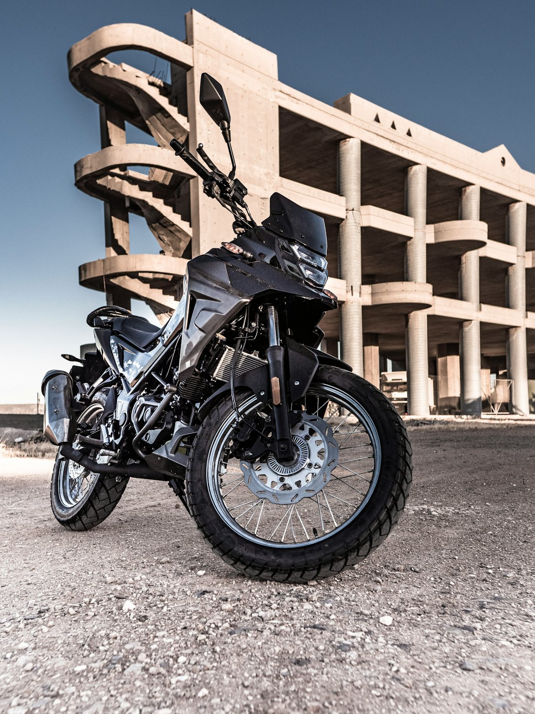 black and gray motorcycle parked beside brown wooden fence during daytime