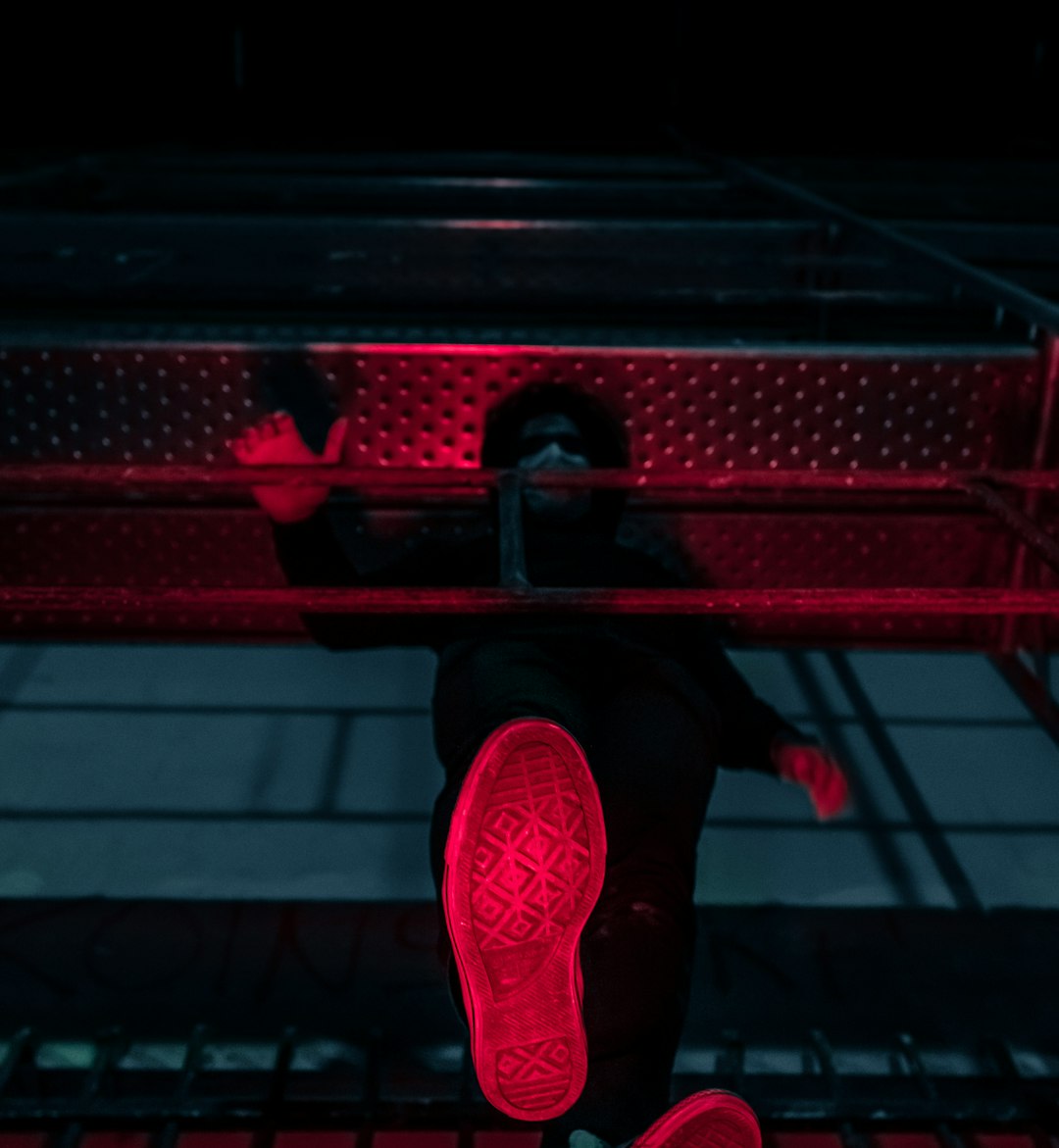 person in red sneakers standing on red metal frame