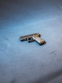 Close-up of a sleek handgun resting on a wooden display table under warm lighting.