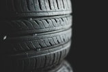 Several stacked tires with visible tread patterns create a textured and industrial look. The background is dark, emphasizing the contrast and details of the rubber surfaces.