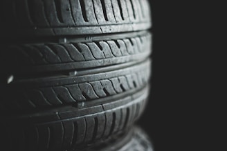 Several stacked tires with visible tread patterns create a textured and industrial look. The background is dark, emphasizing the contrast and details of the rubber surfaces.