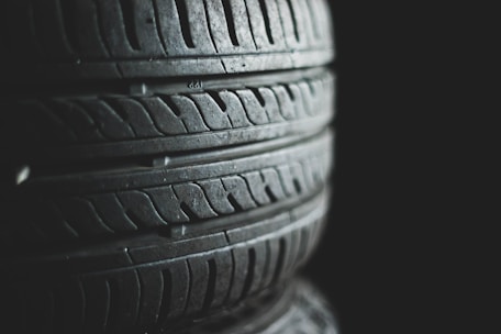 Several stacked tires with visible tread patterns create a textured and industrial look. The background is dark, emphasizing the contrast and details of the rubber surfaces.