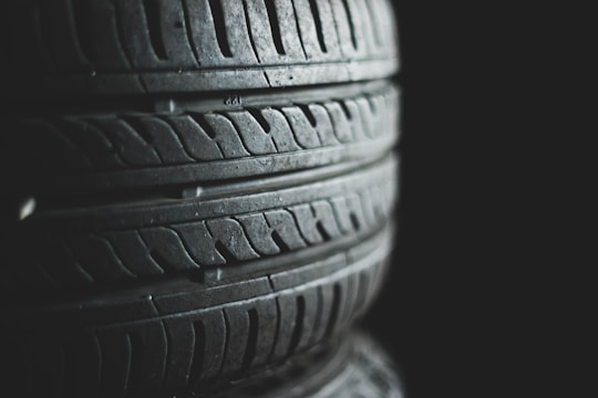Several stacked tires with visible tread patterns create a textured and industrial look. The background is dark, emphasizing the contrast and details of the rubber surfaces.