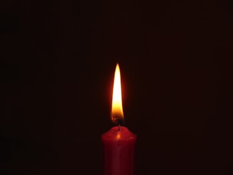 A cozy memorial candle featuring a red cardinal design, flickering gently.