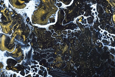 Abstract liquid black marble texture with flowing gold and electric teal veins.