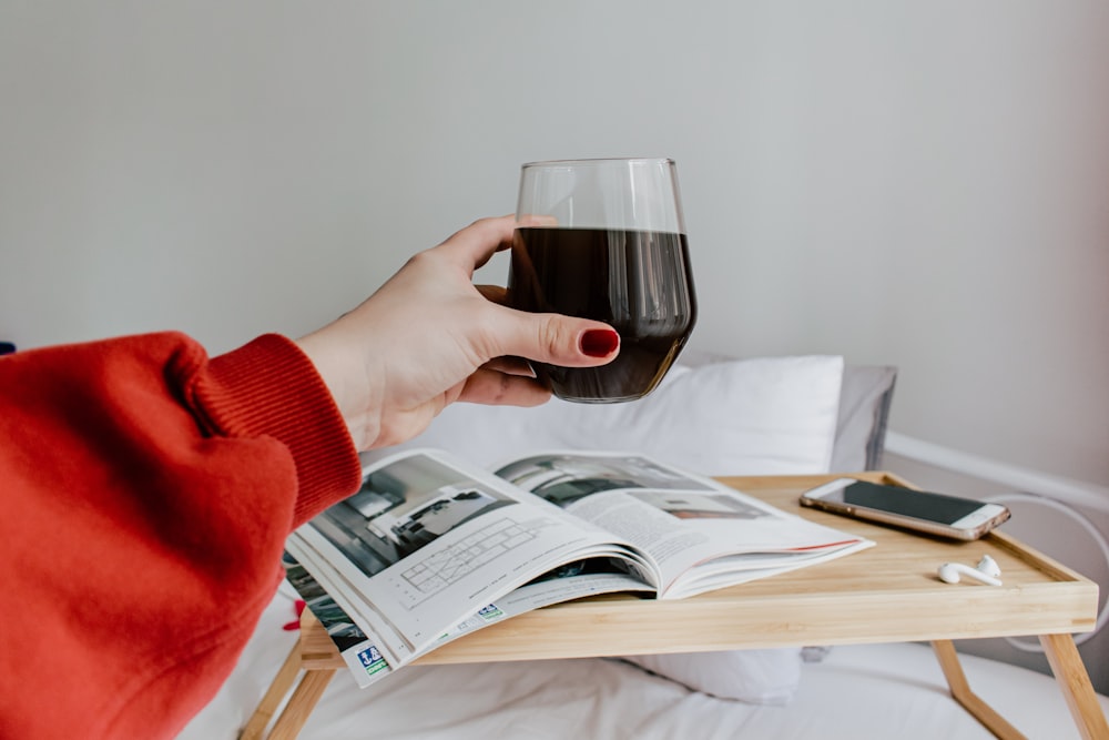 person holding clear wine glass with red wine