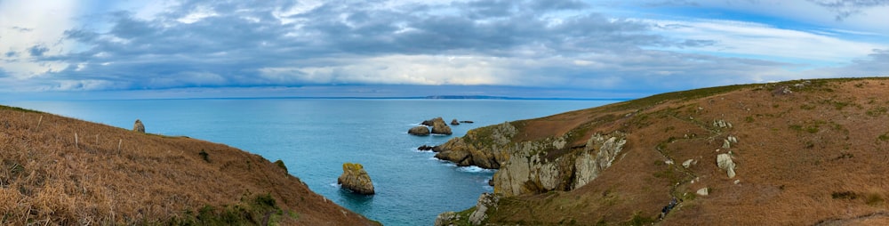 brown rock formation on sea under white clouds during daytime