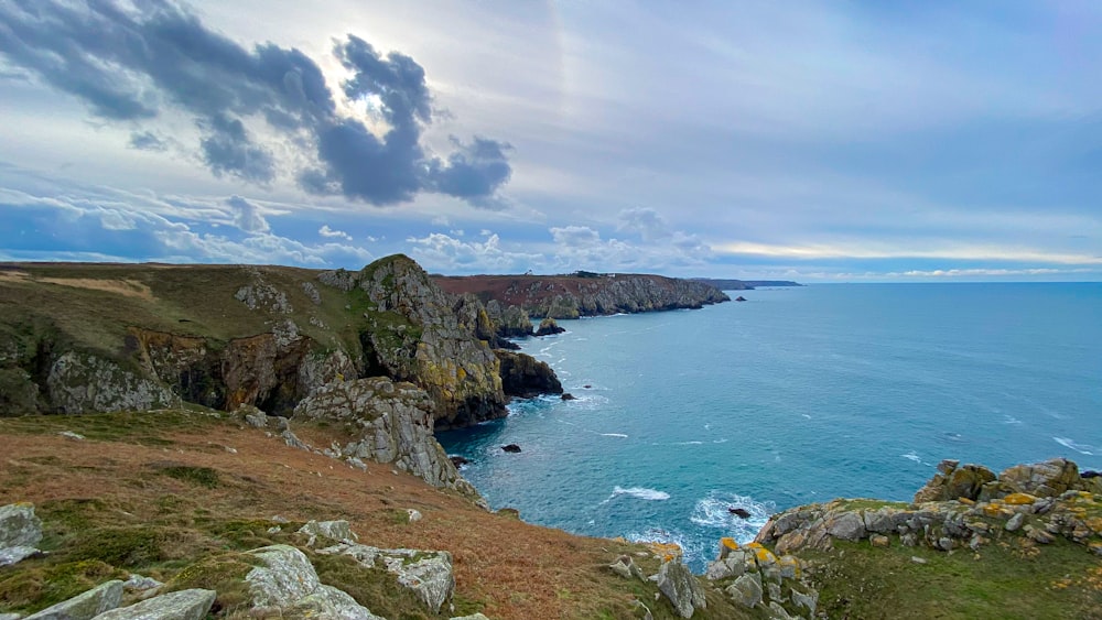 green and brown mountain beside blue sea under blue sky during daytime