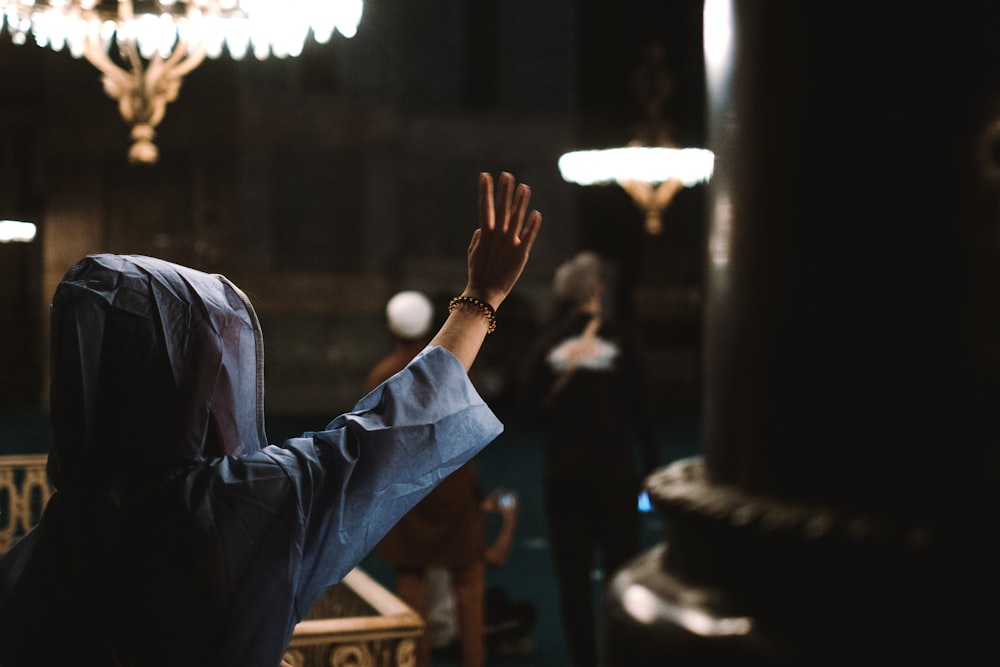 person in blue long sleeve shirt raising his hand