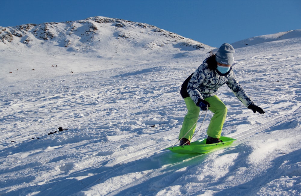 man in black jacket and green pants riding green snowboard on snow covered mountain during daytime