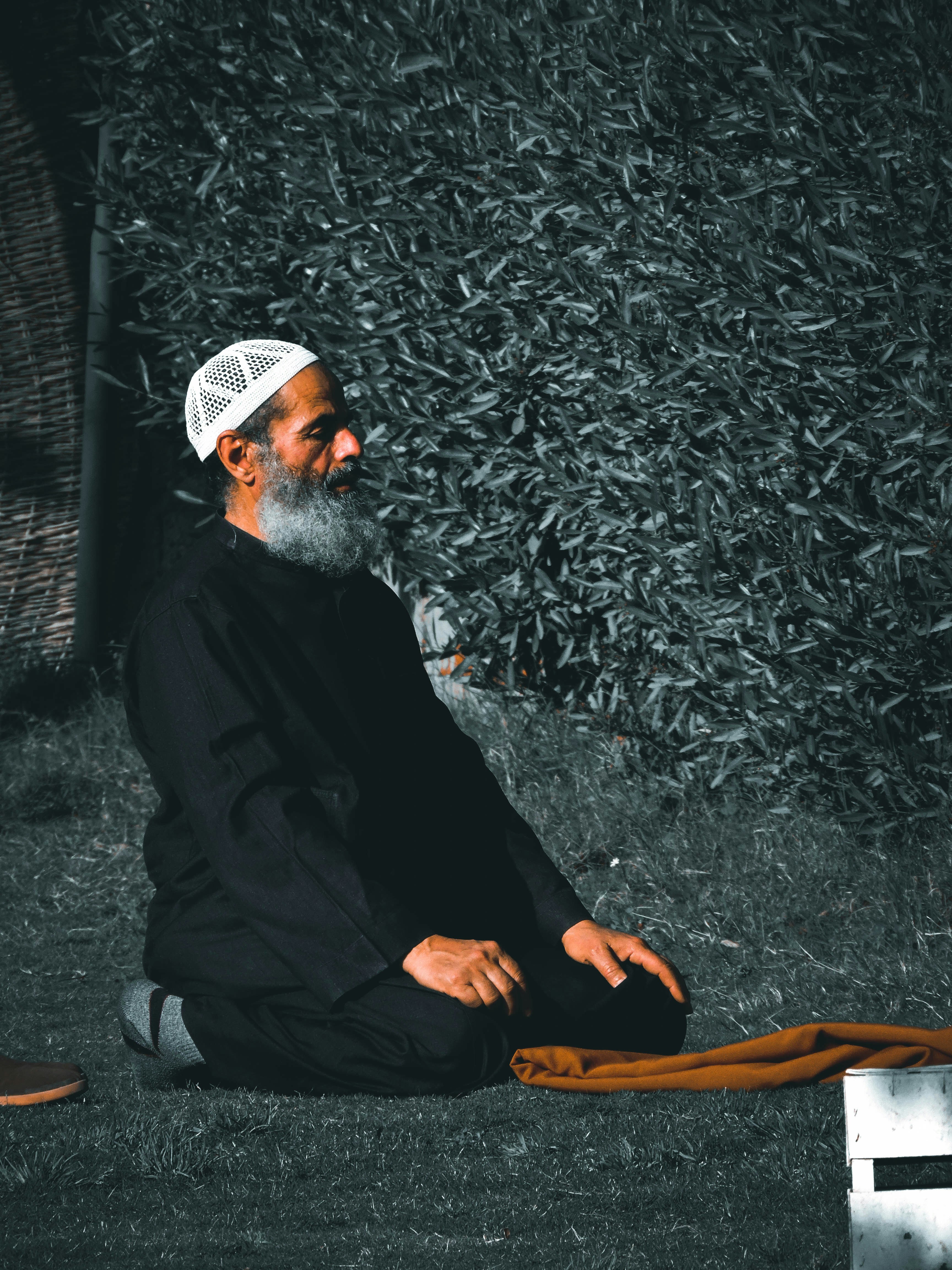 man in black thobe sitting on brown wooden chair