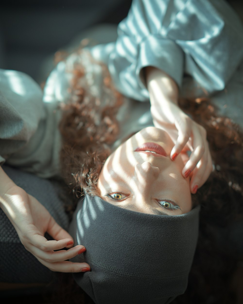 woman in blue and white long sleeve shirt covering her face with black knit cap