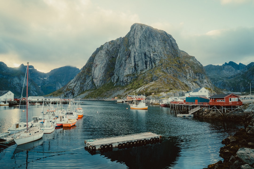 white and red boat on sea near mountain during daytime