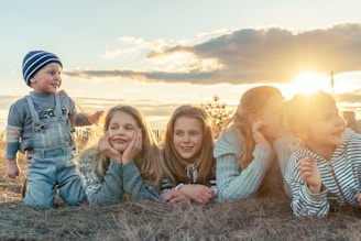 3 women sitting on grass field during sunset