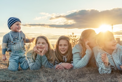 3 women sitting on grass field during sunset