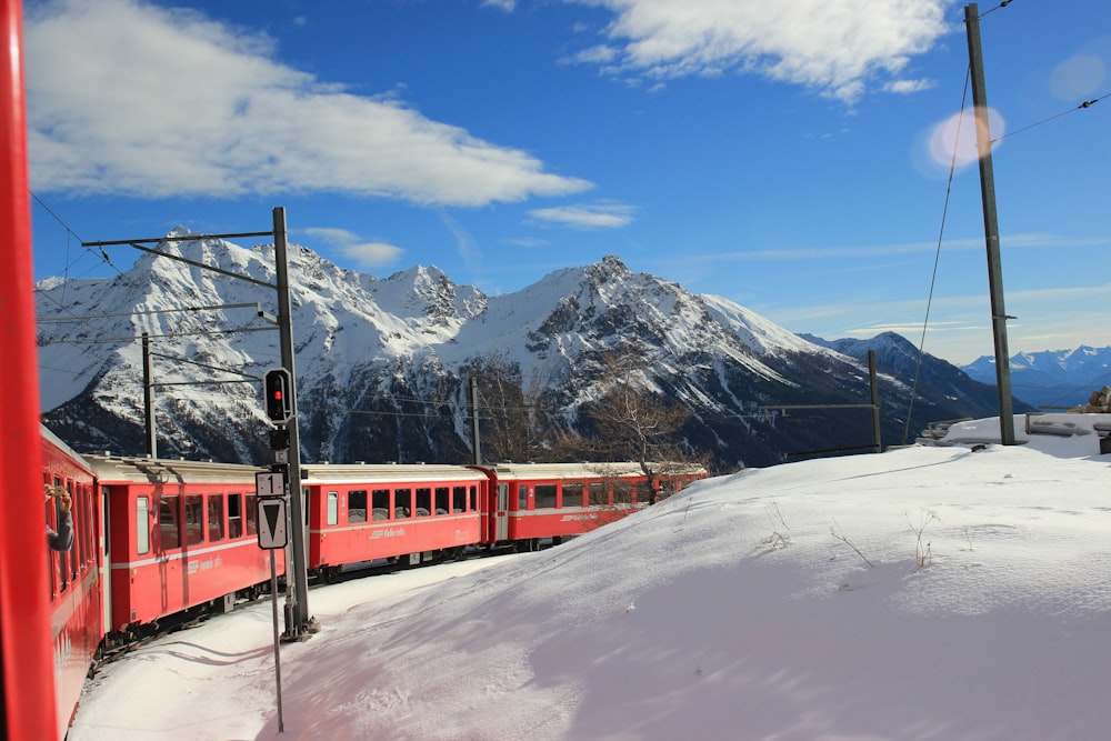 red train on snow covered ground near snow covered mountain during daytime