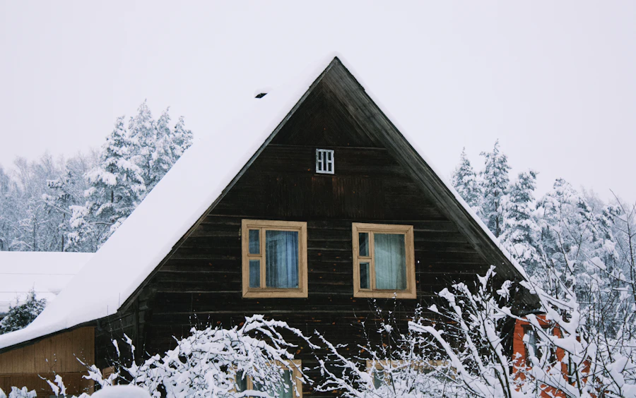A dark wooden house with a steep snowy roof