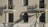 A firefighter wearing a helmet and protective gear is positioned on a ladder leaning against a building facade. The structure features two balconies with shadows cast by the railings. The firefighter appears to be reaching towards the icicles hanging from one of the balconies.