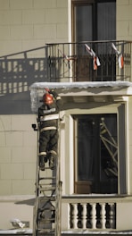 a man on a ladder painting a building