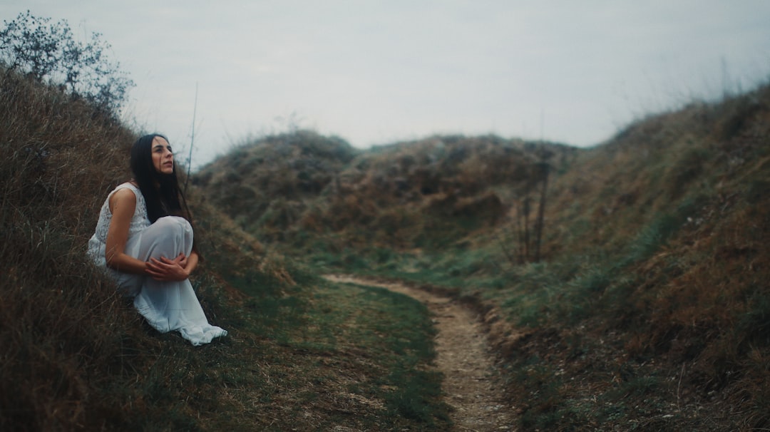 woman in white dress walking on green grass field during daytime