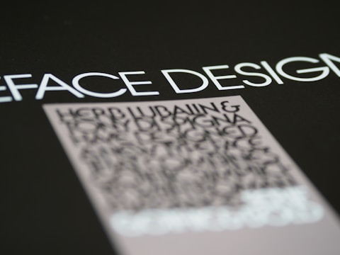 Text in a bold, modern font is prominently displayed against a dark background, with emphasis on the words 'FACE DESIGN'. Below, there is a block of smaller, blurry text that appears to be more detailed but is less legible.