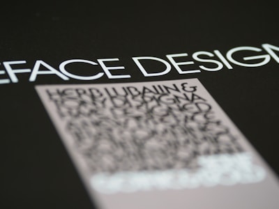 Text in a bold, modern font is prominently displayed against a dark background, with emphasis on the words 'FACE DESIGN'. Below, there is a block of smaller, blurry text that appears to be more detailed but is less legible.