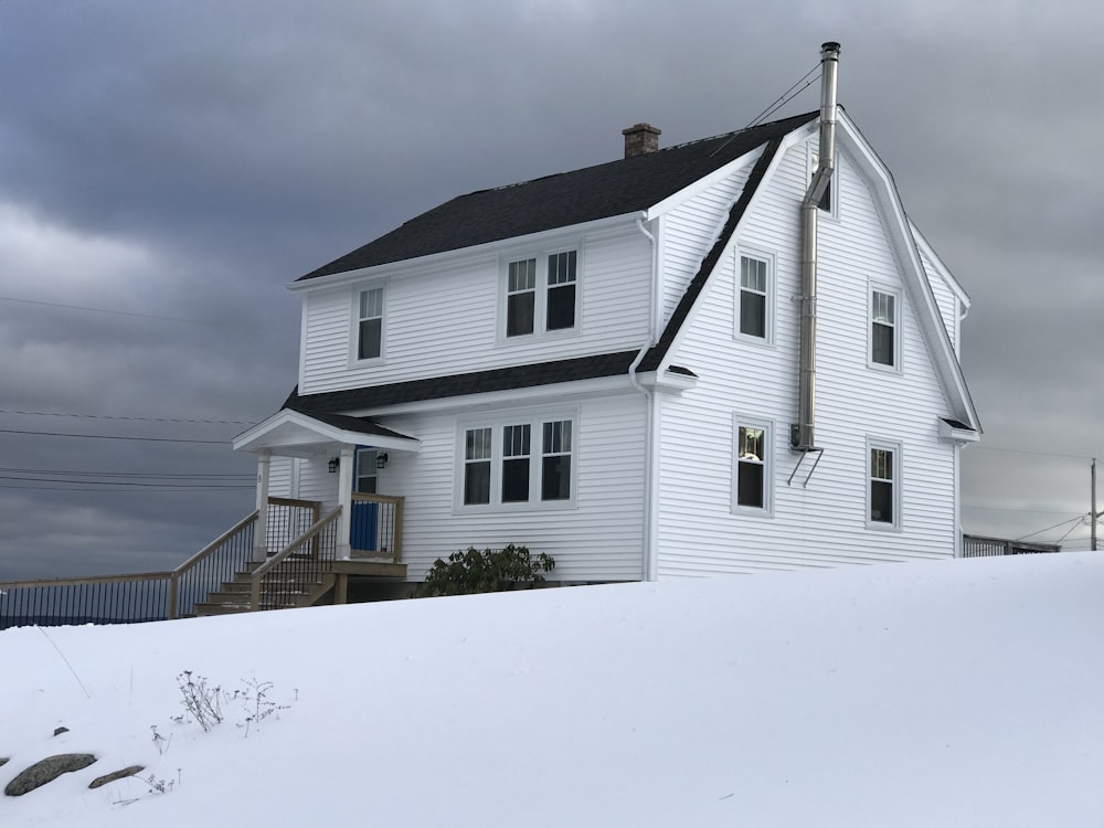 회색 흐린 하늘 아래 눈 덮인 땅에 하얀 목조 주택
