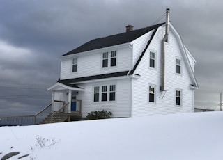 white wooden house on snow covered ground under gray cloudy sky