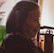 A smiling elderly woman receiving gentle support from a friendly caregiver in a bright, cozy living room.