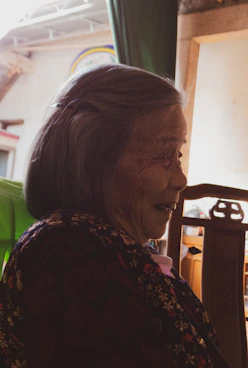 A warm caregiver gently assisting an elderly woman with a smile in a cozy home setting.