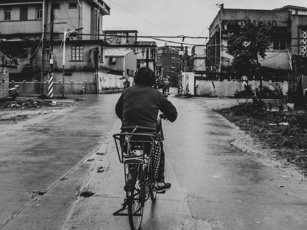 man riding on bicycle in grayscale photography